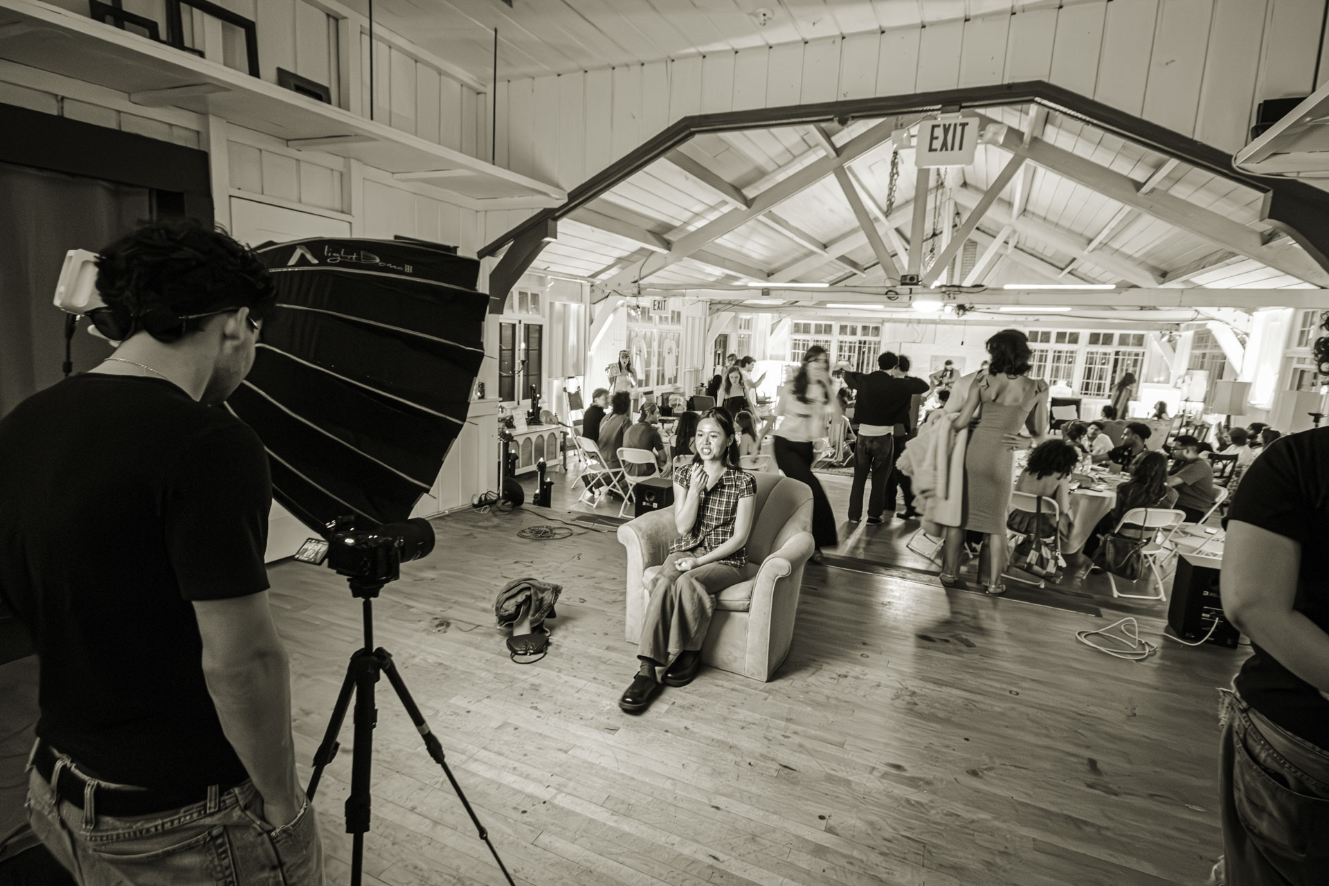 A crew shooting an interview setup with lighting and camera in a large open room