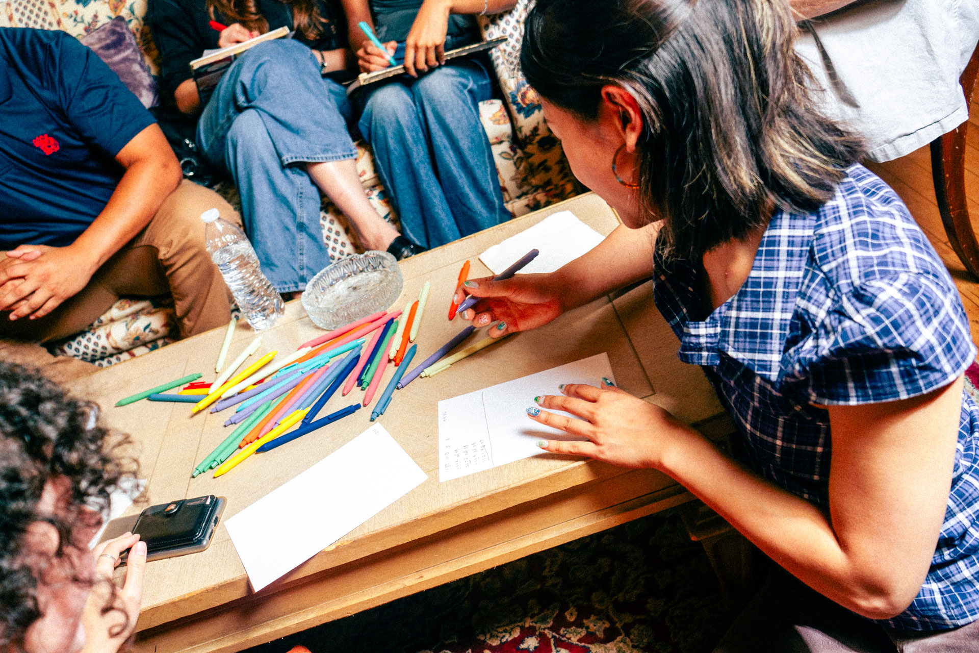 Members drawing with colored pens around a low table