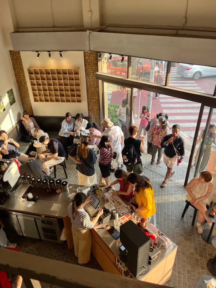 Café counter and coffee bar with guests ordering and sitting inside a bright storefront